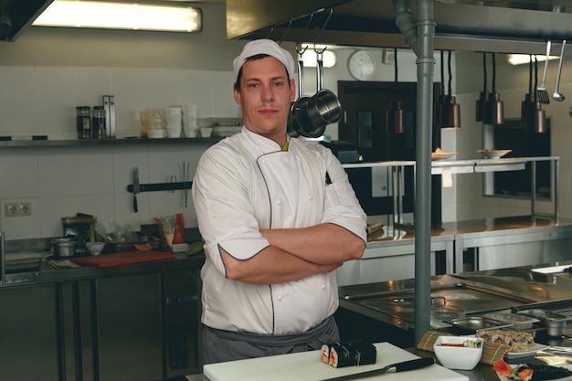 Portrait of handsome male chef in uniform standing on kitchen of restaurant