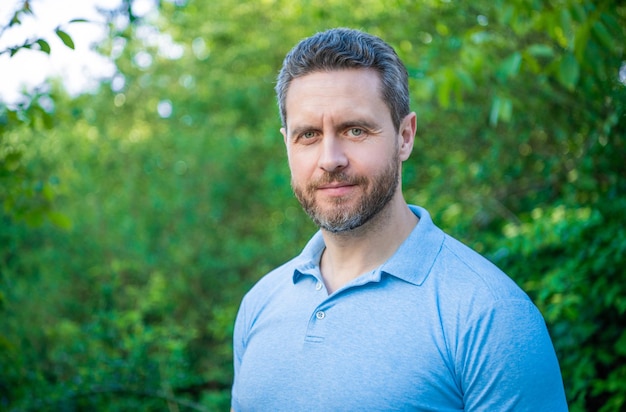 Portrait of handsome man in blue tshirt natural background copy space