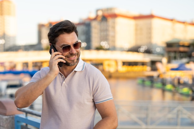 Portrait of handsome man chatting on phone outdoor stylish man talking on phone dressed in polo fash