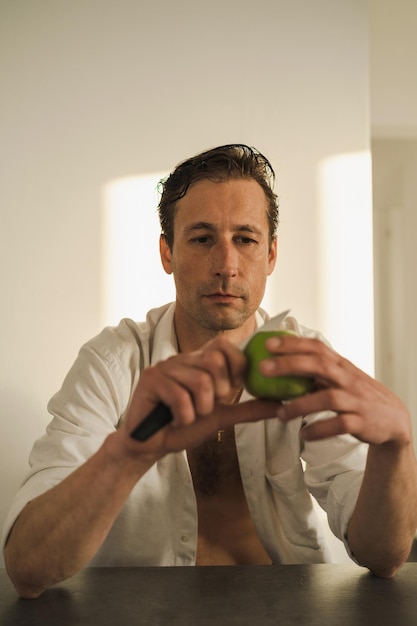 Portrait of handsome man cutting and eating apple