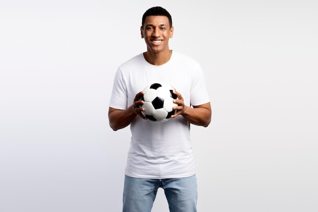 Portrait of handsome man holding soccer ball at his hands with smiling positive expression