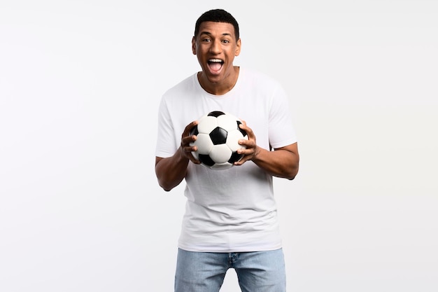 Portrait of handsome man holding soccer ball at his hands with smiling positive expression