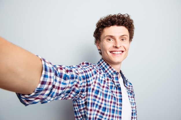 Portrait of handsome man making selfie on grey