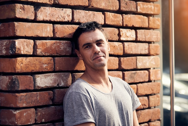 Portrait of handsome man standing in the street near brick wall