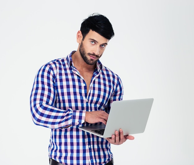 Portrait of a handsome man using laptop computer isolated on a white wall and looking at front