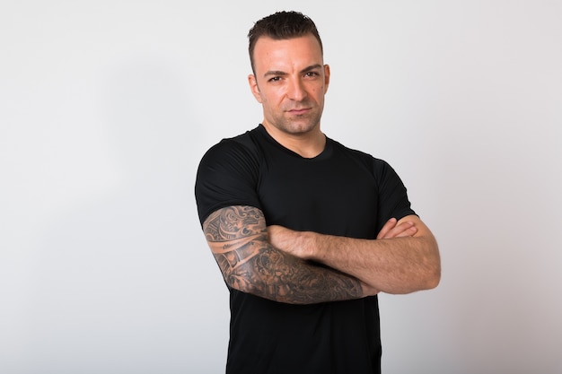 Portrait Of Handsome Man With Tattoos Against White wall