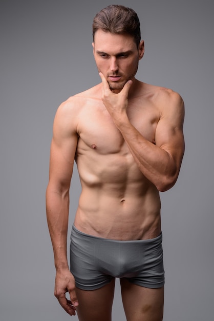 portrait of handsome muscular shirtless man on gray