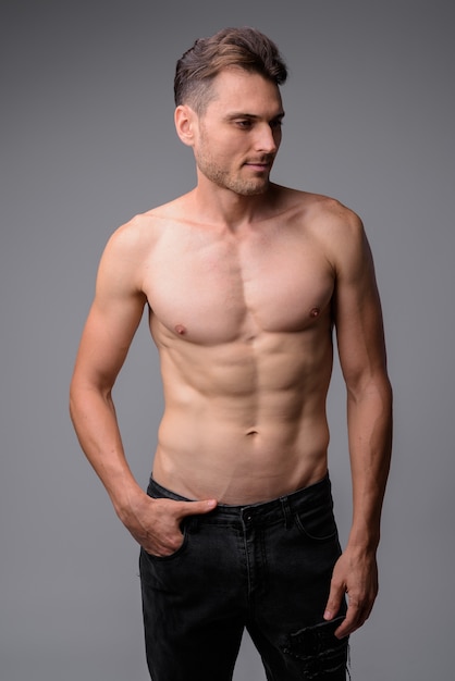 portrait of handsome muscular shirtless man on gray