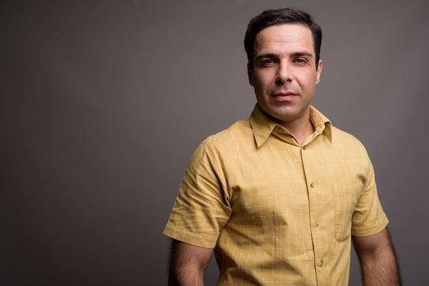 Portrait of handsome Persian man against gray wall