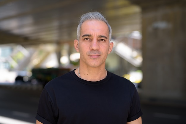 Portrait of handsome Persian man with gray hair in the city streets outdoors