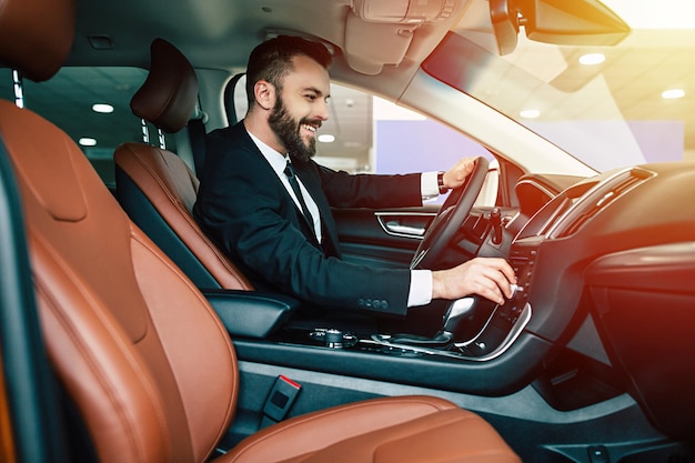 Portrait of an handsome positive smiling business man driving his car