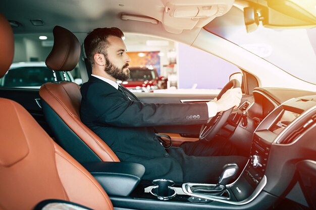 Portrait of an handsome positive smiling business man driving his car