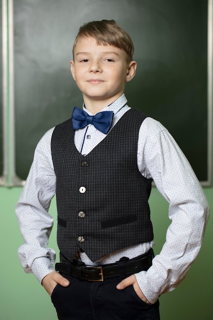 Portrait of a handsome schoolboy in elegant clothes at the blackboard