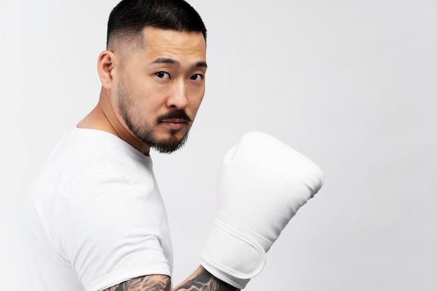 Portrait of handsome serious asian man boxer wearing white boxing gloves looking at camera