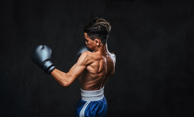 Portrait of a handsome shirtless young boxer during boxing exercises, focused on process with serious concentrated facial.