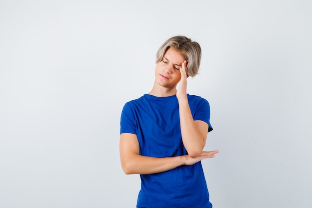 Portrait of handsome teen boy suffering from strong headache in blue t-shirt and looking bothered front view