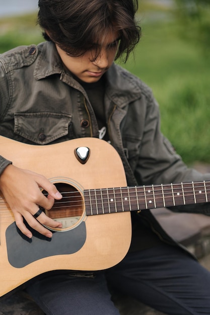 Portrait of handsome teenage boy playing guitar outdoor boy using classic guitar male alone making