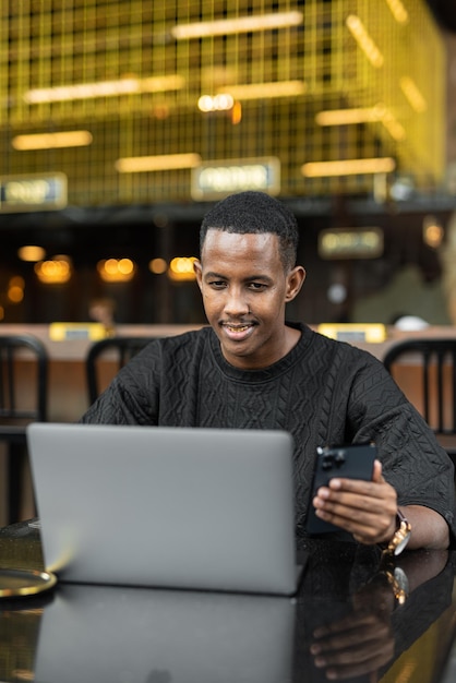 Portrait of handsome young African man using laptop computer in coffee shop