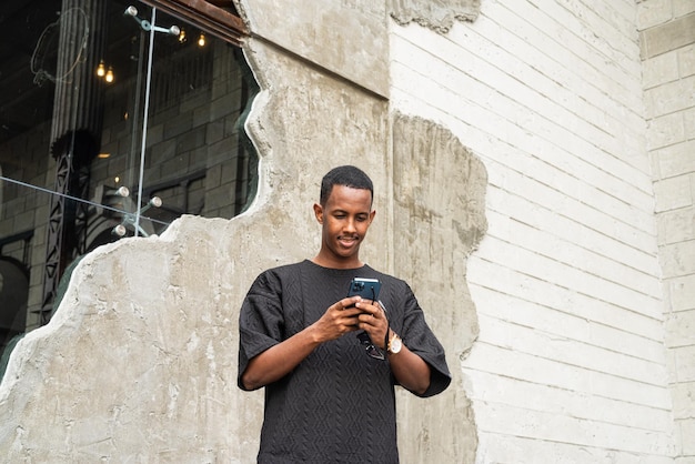 Portrait of handsome young African man using mobile phone outdoors