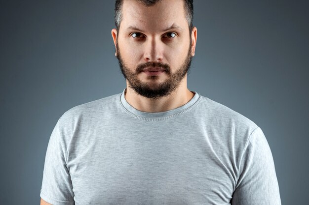 portrait Handsome young bearded man on a gray surface.