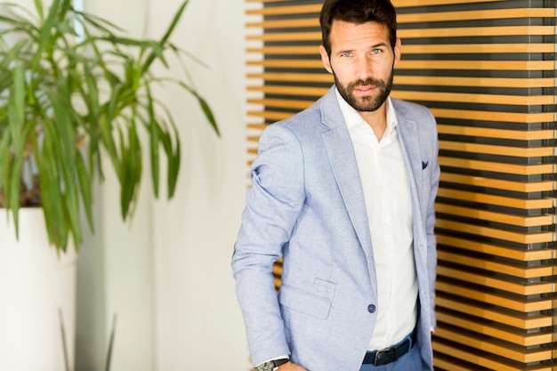 Portrait of handsome young businessman standing against wall