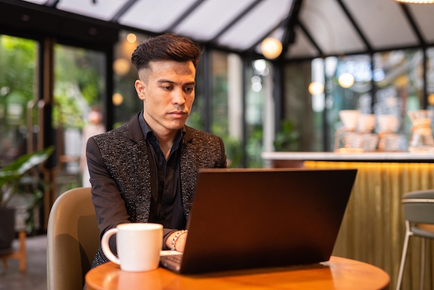 Portrait of handsome young businessman using laptop in coffee shop