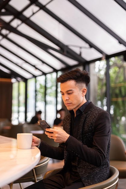 Portrait of handsome young businessman using phone in coffee shop