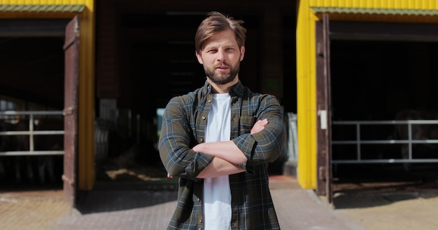 Portrait of a handsome young farmer in shirt looking at camera in background of dairy farm Agricultural industry husbandry concept