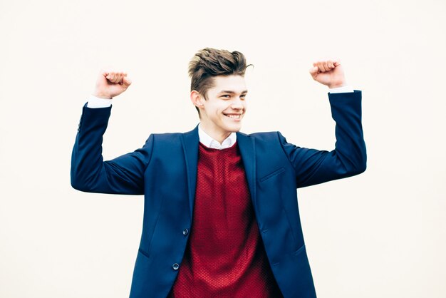 Portrait of handsome young guy with stylish haircut, in suit, rejoices or celebrates victory isolated on white background