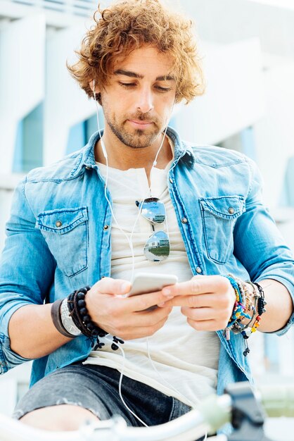 Portrait of Handsome young man smiling when he is using his mobile in the street.