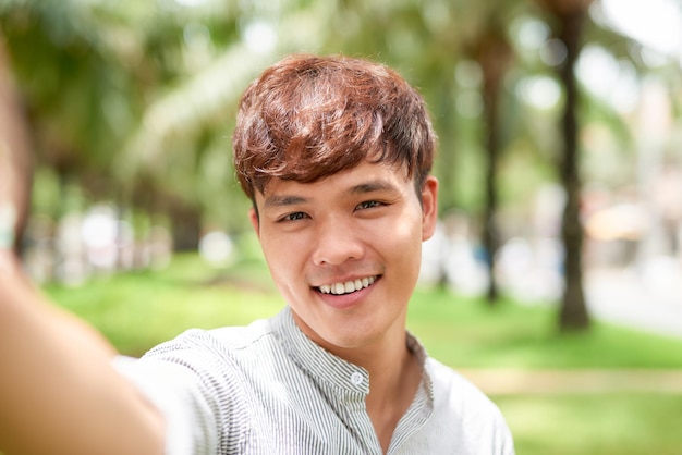 Portrait of a handsome young man taking a selfie with vintage camera