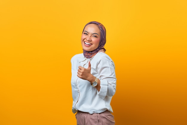 Portrait of happiness Asian woman showing thumbs up over yellow background