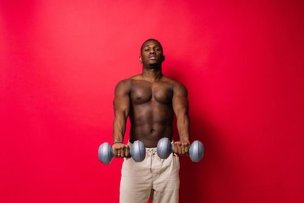 Portrait of a happy african man with dumbbells over red and black background