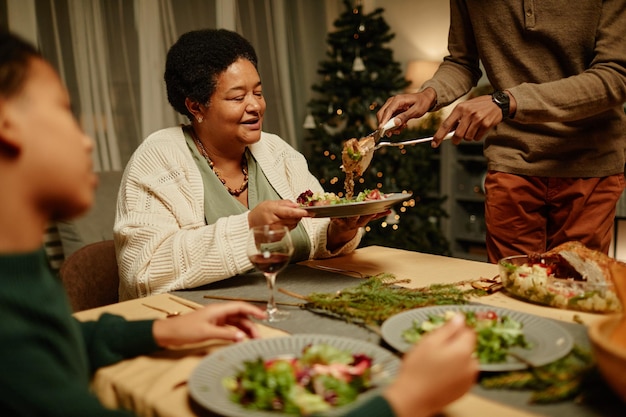 Portrait of happy africanamerican grandmother enjoying food during christmas dinner with family