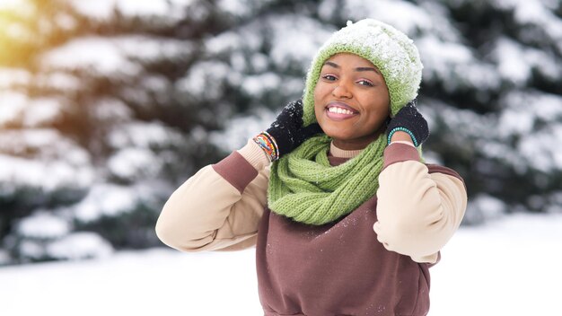 Portrait of happy afro american young woman at winter snowy day in snow park smile