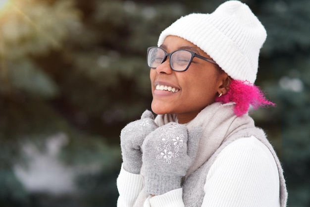 Portrait of happy afro american young woman at winter snowy day in snow park smile