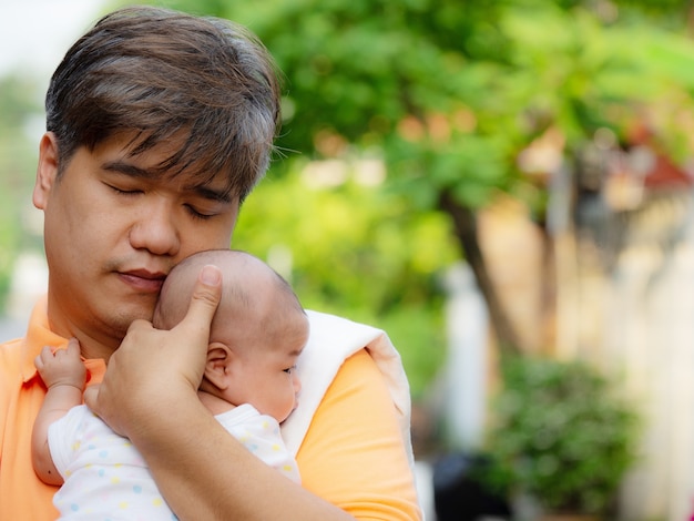 Portrait of happy Asia father holding his newborn sweet baby dressed in white clothes.