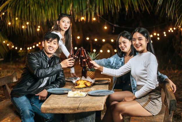 Portrait of Happy Asian friends having dinner party together Young people sitting at bar table toasting beer glasses dinner outdoor People food drink lifestyle new year celebration concept