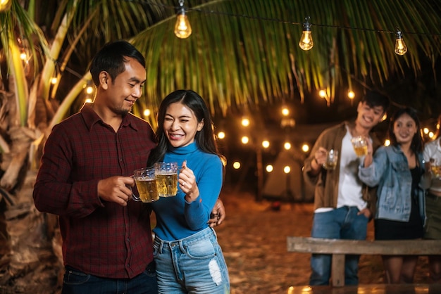 Portrait of Happy Asian friends having dinner party together Young people toasting beer glasses dinner outdoor People food drink lifestyle new year celebration concept