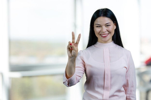 Portrait of happy asian woman showing victory sign