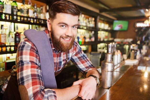 Portrait of happy attractive young bartender with shaker in pub