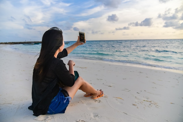 Portrait of happy beautiful girl takes a photo Selfie at Maafushi island, Maldives