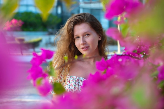 Portrait of happy beautiful girl young positive woman is smelling beautiful pink flowers in the