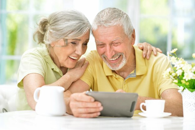 Portrait of happy beautiful senior couple using tablet