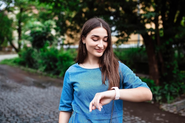 Portrait of happy beautiful young girl smiling looking and pointing finger at her smart watch Beautiful woman looking at her watch