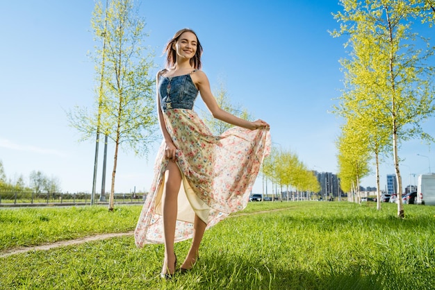 Portrait happy beautiful young woman relaxing in park in long dress Joyful