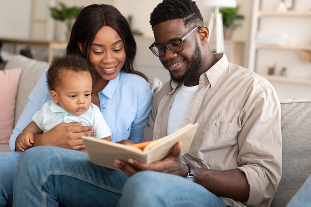 Portrait of happy black family reading book for kid