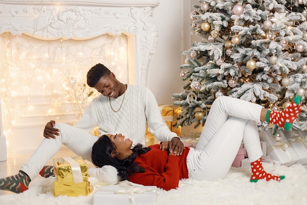 Portrait of happy black woman laying on a lap of her boyfriend near Christmas tree