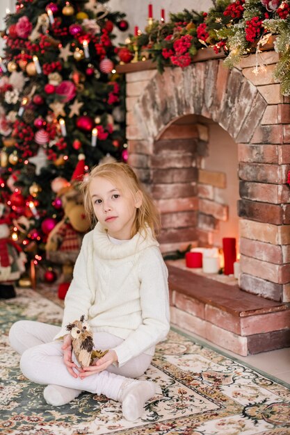  portrait of happy blonde child girl in white sweater siting on the floor