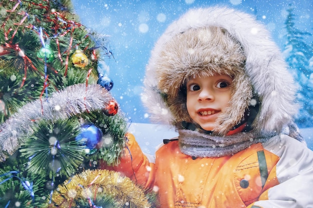 Portrait of happy boy near the Christmas tree with gifts